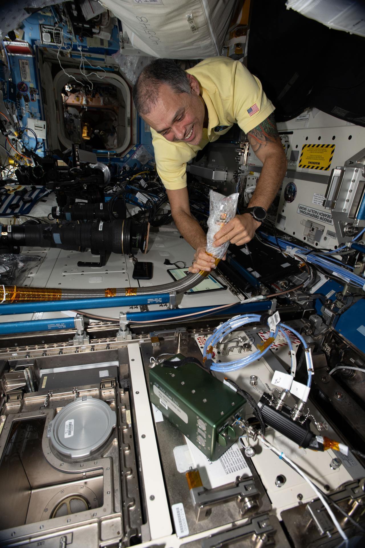 NASA astronaut and Expedition 75 flight engineer Anil Menon tests and fits components of a new cooling system, called the Supplemental Heat Rejection Evaporative Cooler, that will soon be installed in the Destiny laboratory module.