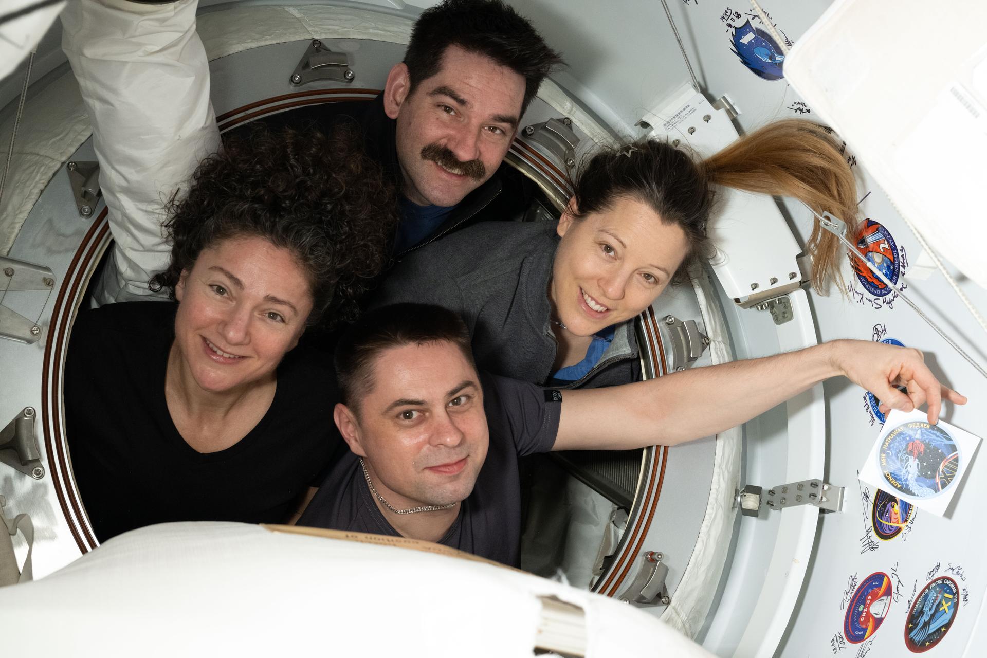 The four members of NASA's SpaceX Crew-12 mission pose for a portrait inside the vestibule between the SpaceX Dragon spacecraft and the International Space Station. Clockwise from left are, NASA astronauts Jessica Meir and Jack Hathaway, ESA (European Space Agency) astronaut Sophie Adenot, and Roscosmos cosmonaut Andrey Fedyaev who is displaying their mission's insignia sticker.