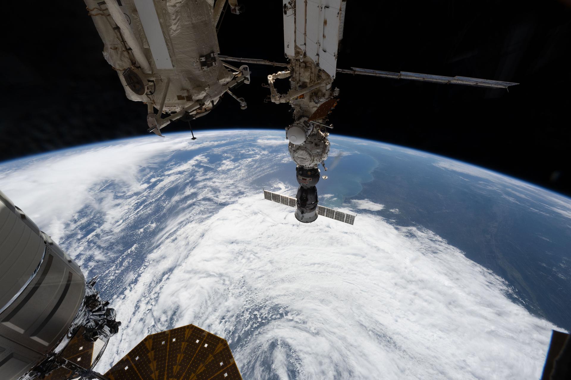 iss075e0153938 (Sept. 28, 20267) --- At center, the Soyuz MS-29 crew spacecraft is pictured docked to the Prichal module as the International Space Station orbited 263 miles above a cloudy southern Europe. Credit: ESA/Sophie Adenot