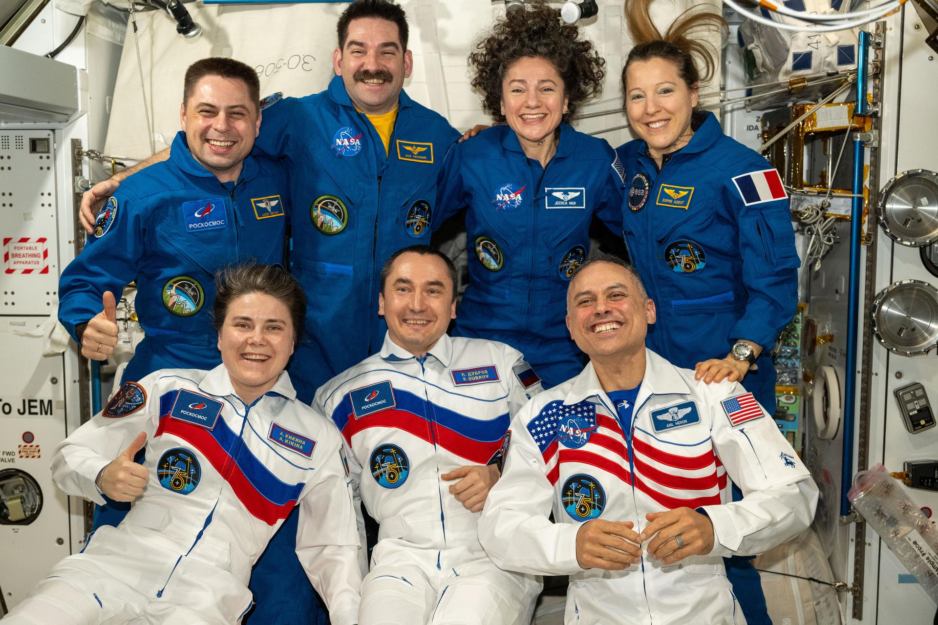 iss075e0157371 (Oct. 2, 2026) --- Seven of the Expedition 75 crew members take a team portrait while waiting for SpaceX Crew‑13 to enter the International Space Station. In the front row from left are Roscosmos cosmonauts Anna Kikina and Pyotr Dubrov and NASA astronaut Anil Menon. In the back row are Roscosmos cosmonaut Andrey Fedyaev, NASA astronauts Jack Hathaway and Jessica Meir, and ESA (European Space Agency) astronaut Sophie Adenot. Credit: NASA