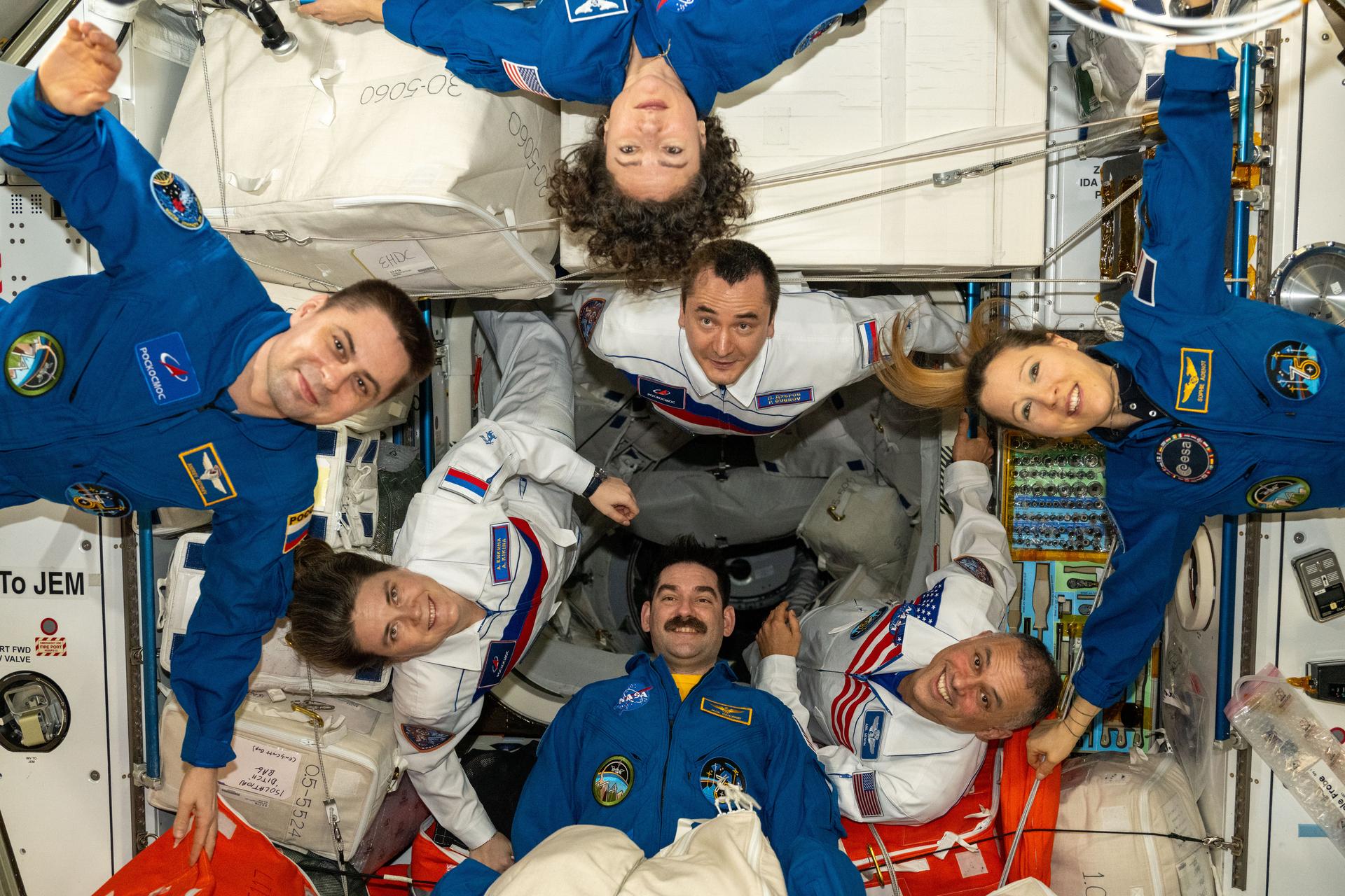 Seven of the Expedition 75 crew members take a team portrait while waiting for SpaceX Crew‑13 to enter the International Space Station. Clockwise from bottom are NASA astronaut Jack Hathaway, Roscosmos cosmonauts Anna Kikina and Andrey Fedyaev, NASA astronaut Jessica Meir, Roscosmos cosmonaut Pyotr Dubrov, ESA (European Space Agency) astronaut Sophie Adenot, and NASA astronaut Anil Menon.