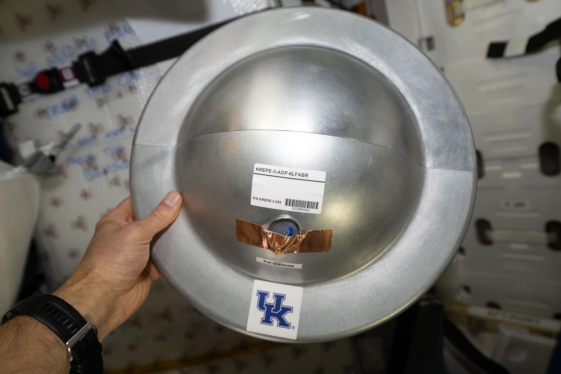 iss075e0185956 (Oct. 7, 2026) --- NASA astronaut Anil Menon holds a KREPE-3 capsule inside the Northrup Grumman Cygnus XL 24 cargo spacecraft. The capsule is one of 10 that will be packed inside Cygnus XL for unberthing and release from the International Space Station. Inside the capsule is an Adaptable Deployable Entry and Placement Technology (ADEPT) heat shield developed at NASA’s Ames Research Center in California’s Silicon Valley. ADEPT is shaped like an umbrella to increase surface area and slow descent. At full size, its design is foldable, making it ideal for deploying payloads that are larger than the rockets that launch them into flight. Credit: NASA/Anil Menon