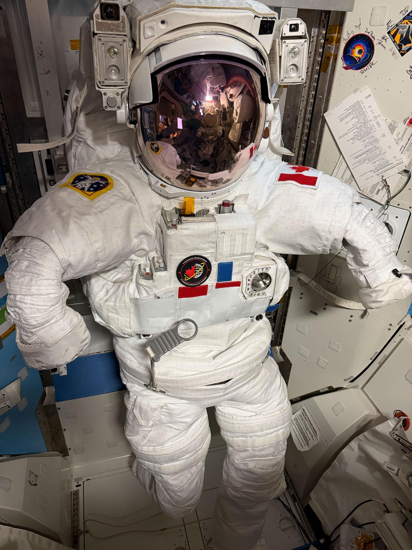 A spacesuit configured for an upcoming spacewalk is pictured inside the International Space Station’s Quest airlock. On the spacesuit’s left shoulder is a patch representing the flag of Canada, the home country of Expedition 75 flight engineer Joshua Kutryk of the Canadian Space Agency (CSA). Kutryk will wear the suit during a spacewalk with NASA astronaut Anil Menon to install a new roll‑out solar array on the orbital outpost’s port‑side truss structure, augmenting the station’s power‑generation system.