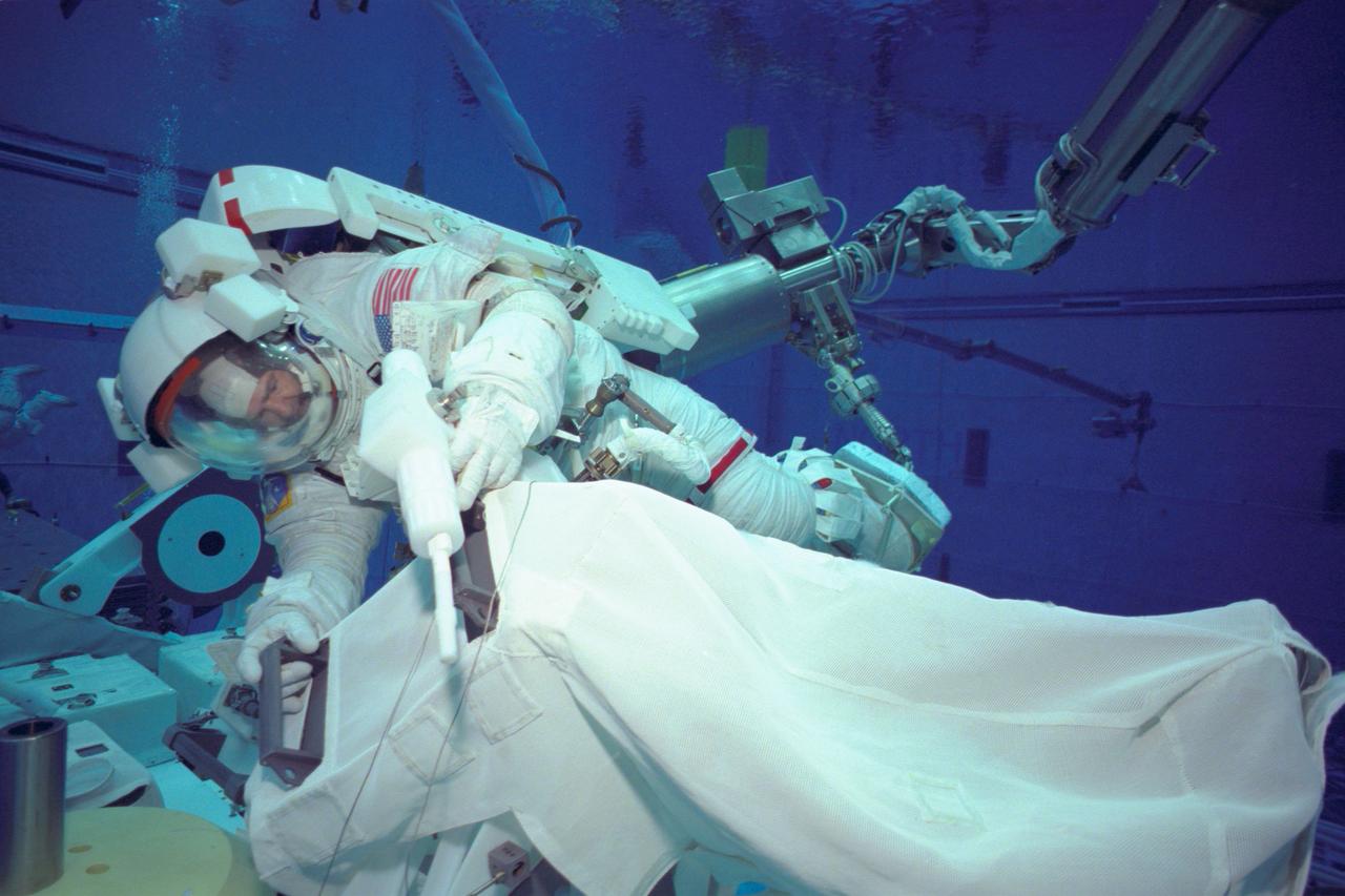 JSC2000-07072 (23 October 2000) --- Equipped with mockup tools and attached to a training version of the shuttle's remote manipulator system (RMS)robotic arm, astronaut Marc Garneau simulates a space walk task in the Neutral Buoyancy Laboratory (NBL). Garneau, an STS-97 mission specialist representing the Canadian Space Agency (CSA), has been assigned an alternate's role for extravehicular activity (EVA) on the ISS 4a mission. The prime EVA crew is composed of astronauts Joseph R. Tanner and Carlos I. Noriega, who are expected to share three different days of space walks during the December mission.