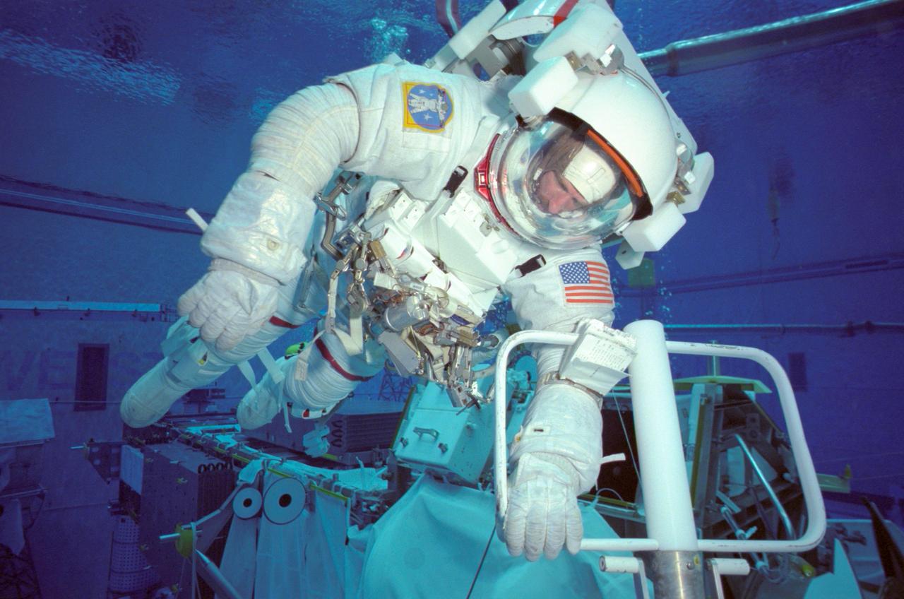 JSC2000-07082 (October 2000)--- Wearing a training version of the shuttle extravehicular mobility unit (EMU) space suit, astronaut Joseph R. Tanner, STS-97 mission specialist, simulates a space walk underwater in the giant Neutral Buoyancy Laboratory (NBL). Tanner was there, along with astronaut Carlos I. Noriega, to rehearse one of three scheduled space walks to make additions to the International Space Station (ISS). The five-man crew in early December will deliver the P6 Integrated Truss Segment, which includes the first US Solar arrays and a power distribution system.