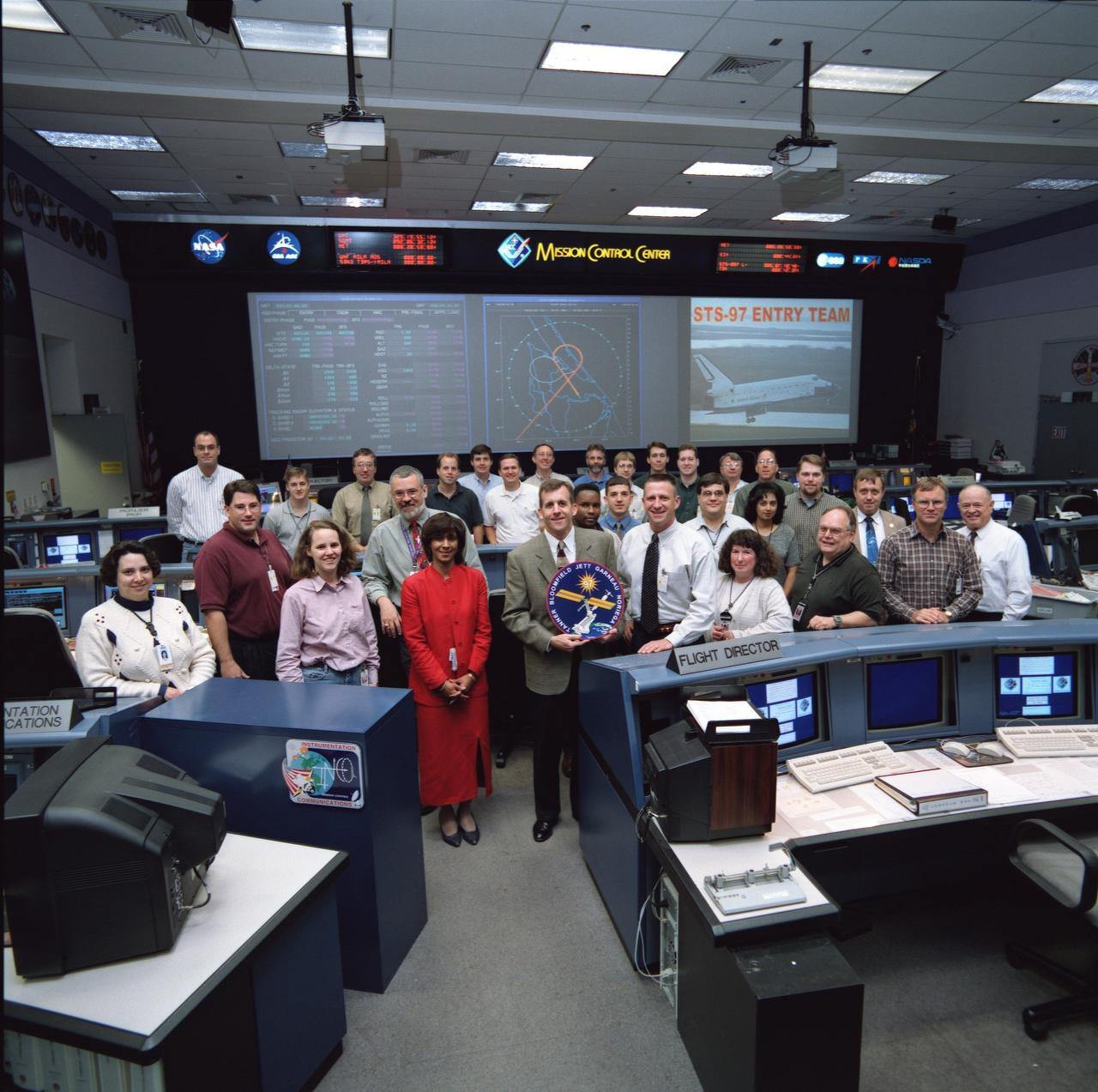JSC2000-07303 (24 November 2000) --- The 30-odd flight controllers supporting the STS-97 entry shift pose for a pre-flight group portrait in the shuttle flight control room in Houston's Mission Control Center (JSC). Entry flight director LeRoy Cain (front center) holds a mission logo.