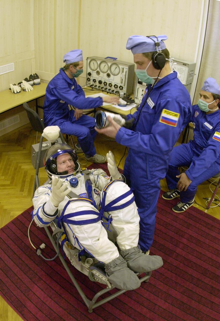 JSC2000-E-27087 (20 October 2000) --- Expedition 1 commander William M. (Bill) Shepherd, wearing a Sokol suit, gets help with his glove before entering the Soyuz spacecraft at Baikonur.  Out of frame are Soyuz pilot Yuri P. Gidzenko and flight engineer Sergei K. Krikalev.