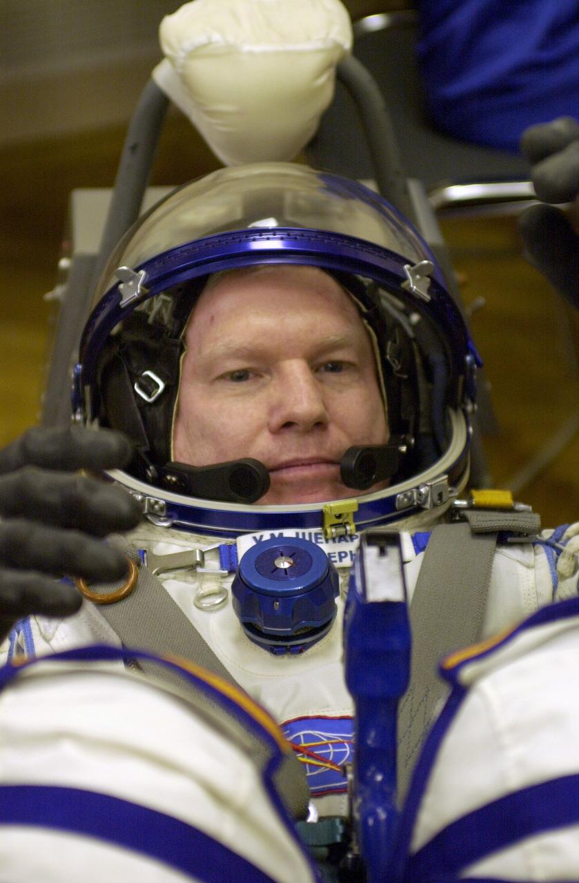 JSC2000-E-27088 (20 October 2000) --- Expedition 1 commander William M. (Bill) Shepherd, wearing a Sokol suit, secures his helmet during a suit-up &quot;dry run&quot; at Baikonur.  Out of frame are Soyuz commander Yuri P. Gidzenko and flight engineer Sergei K. Krikalev.
