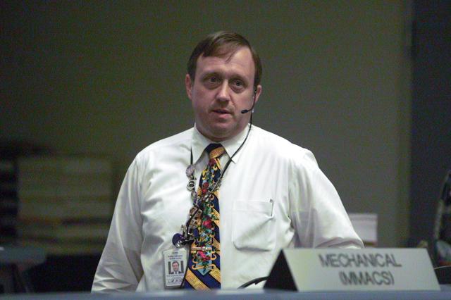 JSC2001-E-12141 (19 April 2001) --- William M. (Bill) Foster, one of the Ground Controllers (GC) for ascent in the flight control room in the Johnson Space Center's Mission Control Center (MCC), discusses a data communications issue with Flight Director LeRoy Cain (not shown) over the voice loops.  He is standing in front of the Mechanical (MMACS) console, which is directly behind the GC console, as he faces the rear of the room to talk with Flight.