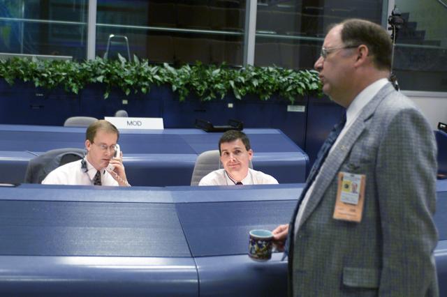 JSC2001-E-25434 (21 August 2001) --- STS-105 flight directors John Shannon (left) and Steve Stich, monitor data at their consoles in the shuttle flight control room (WFCR) in Houston’s Mission Control Center (MCC). Wayne Hale of the Mission Operations Directorate (MOD) is photographed standing in the foreground.