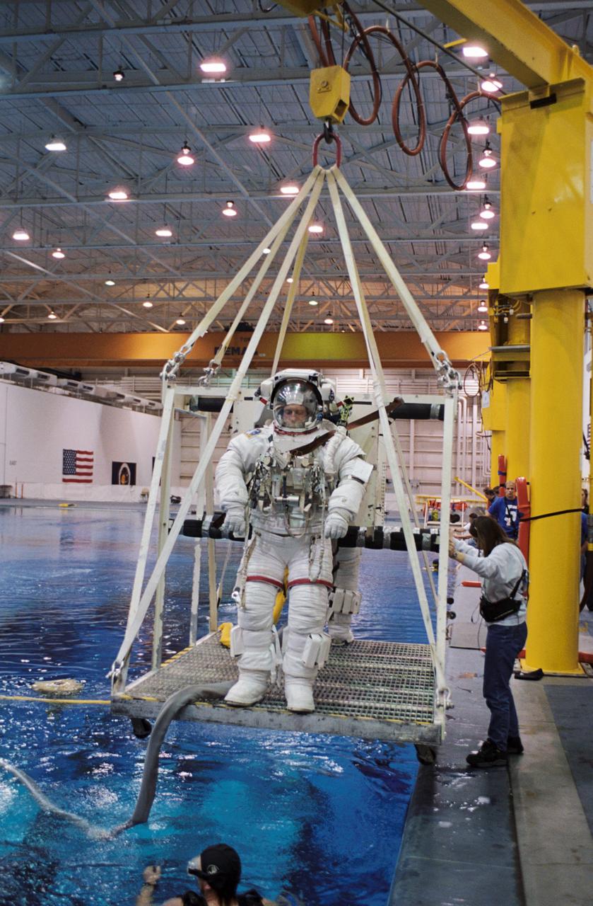 JSC2002-00587 (19 March 2002) --- Astronaut C. Michael Foale and cosmonaut Valery I. Tokarev (partially obscured), Expedition Eight mission commander and flight engineer, respectively, are about to be submerged in the waters of the Neutral Buoyancy Laboratory (NBL) near the Johnson Space Center (JSC). Foale and Tokarev are wearing training versions of the Extravehicular Mobility Unit (EMU) spacesuit. Divers are in the water to assist the astronaut and cosmonaut in their rehearsal, intended to help prepare them for work on the exterior of the International Space Station (ISS). Tokarev represents Rosaviakosmos.