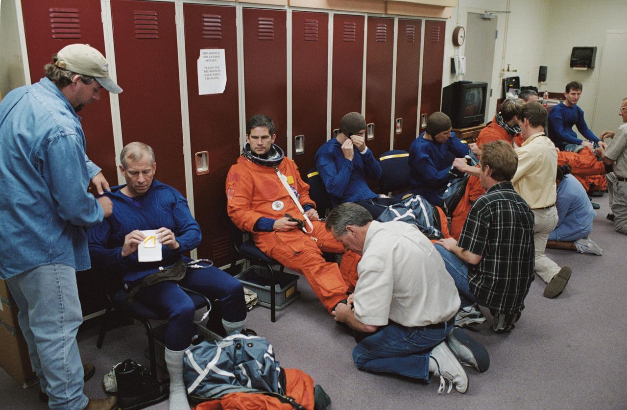 JSC2002-00724 (29 March 2002) --- The STS-111 crewmembers and the Expedition Five crewmembers don training versions of the shuttle launch and entry suit prior to a mission training session in one of the trainer/mockups (out of frame) in the Space Vehicle Mockup Facility at Johnson Space Center (JSC). Seated from the left, the STS-111 crewmembers are astronauts Kenneth D. Cockrell and Paul S. Lockhart, mission commander and pilot, respectively, Philippe Perrin and Franklin R. Chang-Diaz, both mission specialists; along with the Expedition Five crewmembers--astronaut Peggy A. Whitson, flight engineer, and cosmonauts Valeri G. Korzun and Sergei Y. Treschev, mission commander and flight engineer, respectively. Korzun and Treschev represent Rosaviakosmos and Perrin represents CNES, the French Space Agency.
