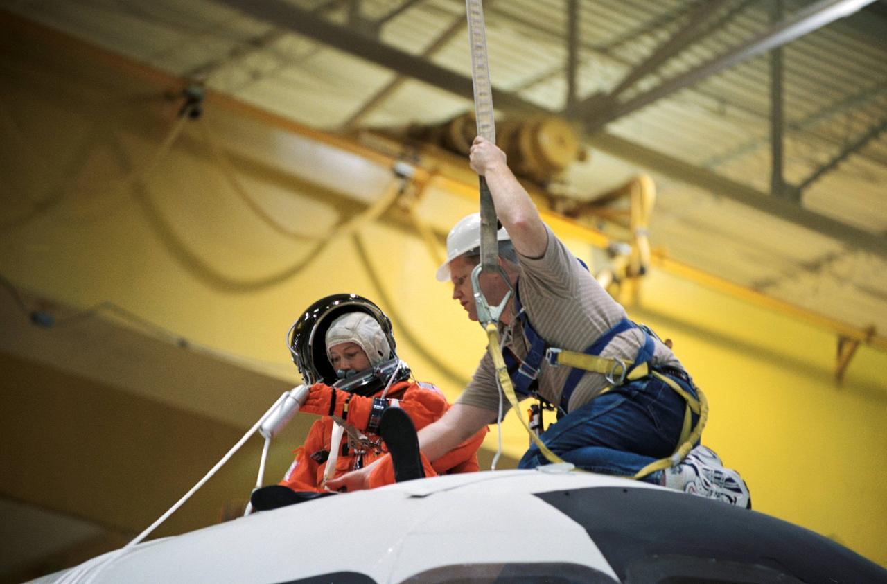 JSC2002-00862 (24 April 2002) --- Astronaut Pamela A. Melroy, STS-112 pilot, uses a device called a Sky genie to simulate rappelling from a troubled shuttle in a training session in the Space Vehicle Mockup Facility at the Johnson Space Center (JSC). The mockup is called the Full Fuselage Trainer (FFT). This exercise trains the crewmembers for procedures to follow in egressing a troubled shuttle on the ground. United Space Alliance (USA) crew trainer Bob Behrendsen assisted Melroy.