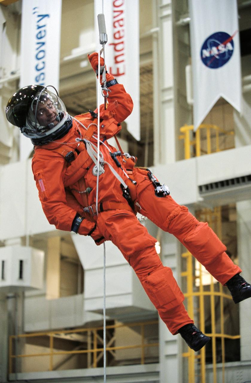 JSC2002-00868 (24 April 2002) --- Astronaut Jeffrey S. Ashby, STS-112 mission commander, wearing a training version of the full-pressure launch and entry suit, lowers himself from a simulated shuttle in trouble during an emergency egress training session in the Space Vehicle Mockup Facility at the Johnson Space Center (JSC).