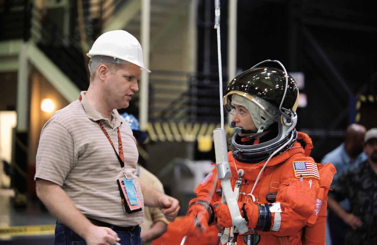 JSC2002-00871 (24 April 2002) --- Astronaut Pamela A. Melroy, STS-112 pilot, is briefed by United Space Alliance (USA) crew trainer Bob Behrendsen on the usage of the Sky-genie, used to lower oneself from a troubled shuttle. The briefing came during a training session in the Space Vehicle Mockup Facility at the Johnson Space Center (JSC). Melroy is wearing a training version of the shuttle launch and entry suit.