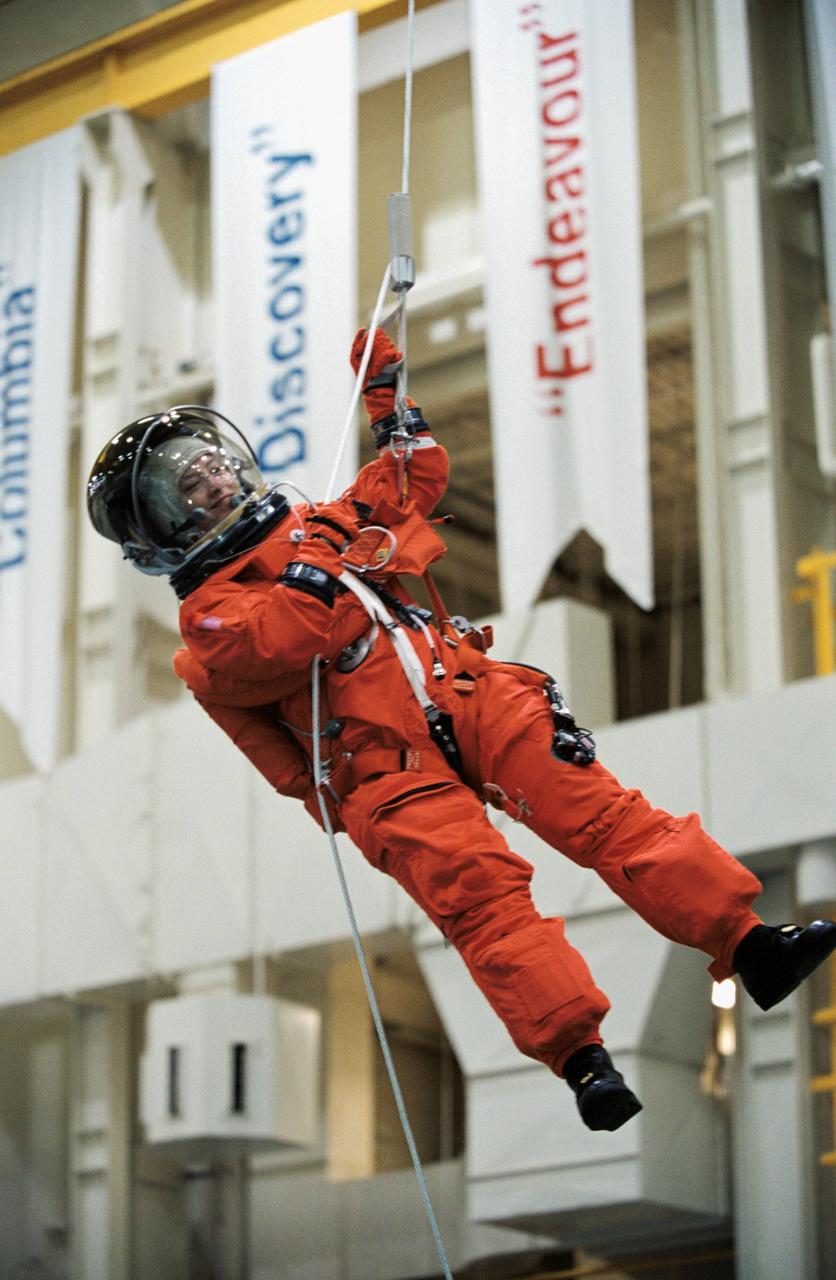 JSC2002-00872 (24 April 2002) --- Astronaut Pamela A. Melroy, STS-112 pilot, wearing a training version of the full-pressure launch and entry suit, lowers herself from a simulated shuttle in trouble during an emergency egress training session. This type training takes place in the Space Vehicle Mockup Facility at the Johnson Space Center (JSC).