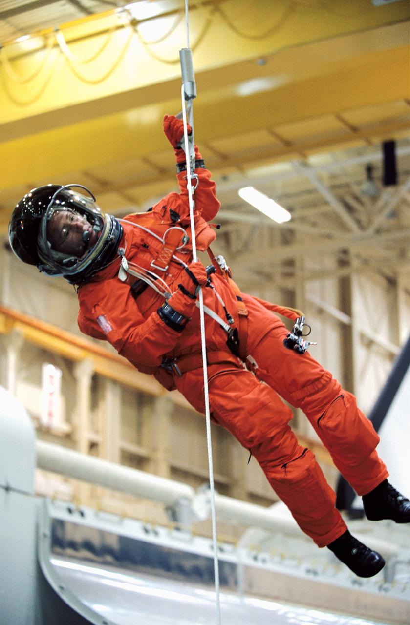 JSC2002-00879 (24 April 2002) --- Astronaut Sandra H. Magnus, STS-112 mission specialist, wearing a training version of the full-pressure launch and entry suit, lowers herself from a simulated shuttle in trouble during an emergency egress training session in the Space Vehicle Mockup Facility at the Johnson Space Center (JSC).