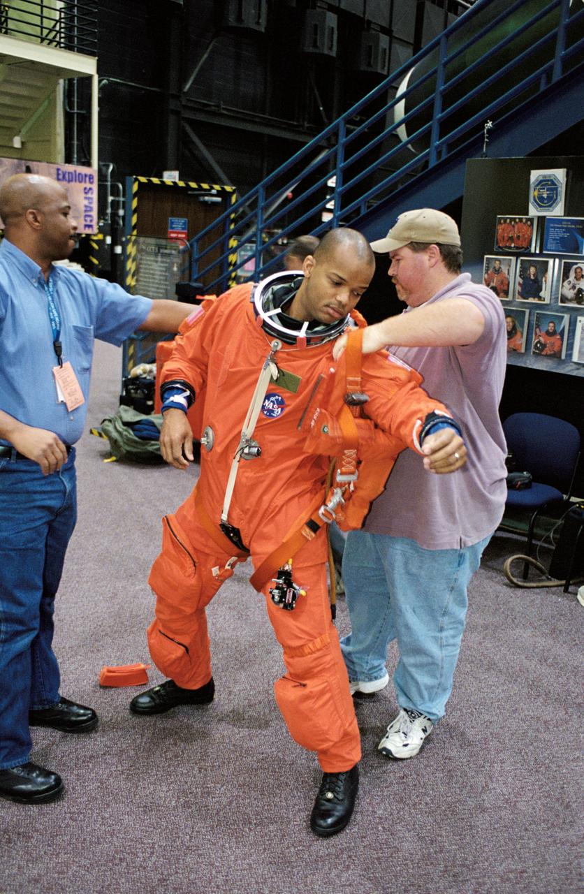 JSC2002-01540 (8 August 2002) --- Astronaut Robert L. Curbeam, Jr., STS-116 mission specialist, dons his training version of the full-pressure launch and entry suit prior to a training session in the Space Vehicle Mockup Facility at the Johnson Space Center (JSC). United Space Alliance (USA) suit technicians Andre Denard (left) and Tommy McDonald assisted Curbeam.