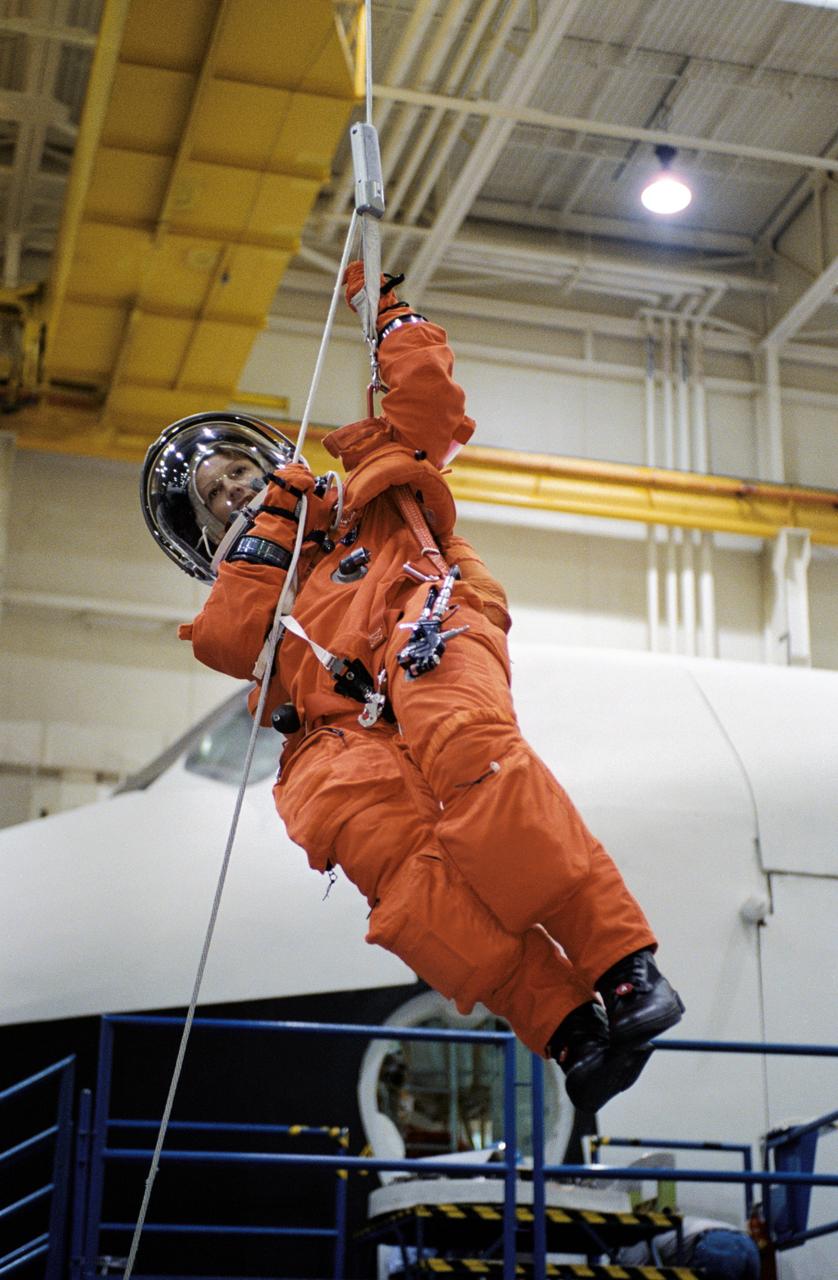 JSC2002-01651 (12 September 2002) --- Astronaut Eileen M. Collins, STS-114 mission commander, wearing a training version of the full-pressure launch and entry suit, lowers herself from a simulated shuttle in trouble during an emergency egress training session in the Space Vehicle Mockup Facility at the Johnson Space Center (JSC).