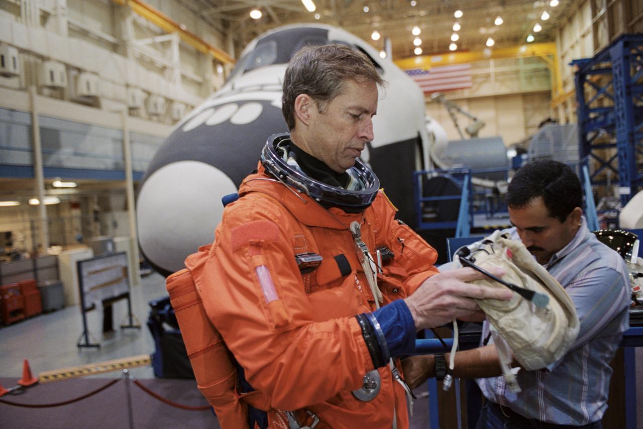 JSC2002-01739 (17 Sept. 2002) --- Astronaut James D. Wetherbee, STS-113 mission commander, dons a training version of the full-pressure launch and entry suit prior to the start of a training session in the Space Vehicle Mockup Facility at the Johnson Space Center (JSC). United Space Alliance (USA) suit technician Raymond Cuevas assisted Herrington.