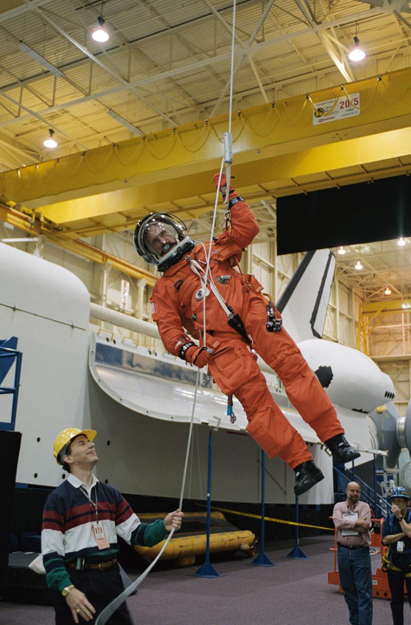JSC2002-02121 (3 December 2002) --- Astronaut Joseph R. (Joe) Tanner, STS-115 mission specialist, uses the Sky-genie to lower himself from a simulated trouble-plagued shuttle in an emergency egress training session in the Space Vehicle Mockup Facility at the Johnson Space Center (JSC). Tanner is wearing a training version of the shuttle launch and entry suit. United Space Alliance (USA) crew trainer David Pogue assisted Tanner.