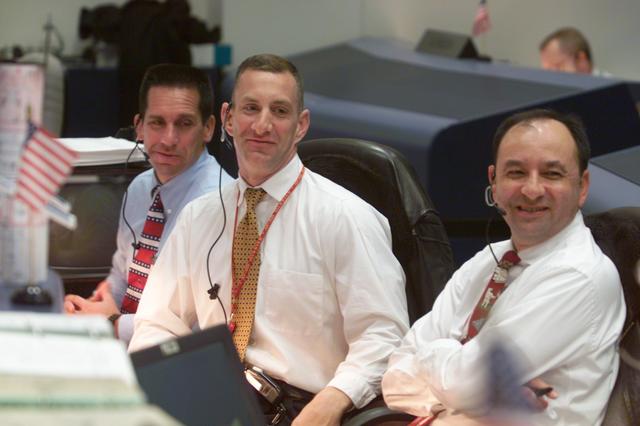 JSC2002-E-08144 (1 March 2002) --- Good news concerning the anticipated launch of STS-109 reaches the Spacecraft Communicator (CAPCOM) console in the Shuttle Flight Control Room of the Johnson Space Center's Mission Control Center. From left, astronauts  William A. Oefelein, Charles O. Hobaugh and Mark L. Polansky, obviously are pleased with the news, possibly connected to improving weather at the launch site for the Space Shuttle Columbia several hundred miles away in Florida.  Astronaut Polansky is ascent CAPCOM and Hobaugh closely monitors the Florida weather for the CAPCOM position.