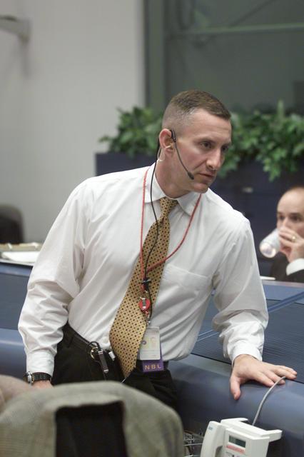 JSC2002-E-08145 (1 March 2002) ---  Astronaut Charles Hobaugh, standing near the Spacecraft Communicator (CAPCOM) console in the Shuttle Flight Control Room of the Johnson Space Center's Mission Control Center, talks with astronaut Mark L. Polansky (out of frame), STS-109 ascent CAPCOM.  They were monitoring the pre-launch situation at the Kennedy Space Center launch site, several hundred miles away.  Hobaugh's duties, among others, were to keep up with weather conditions at and around the launch site.