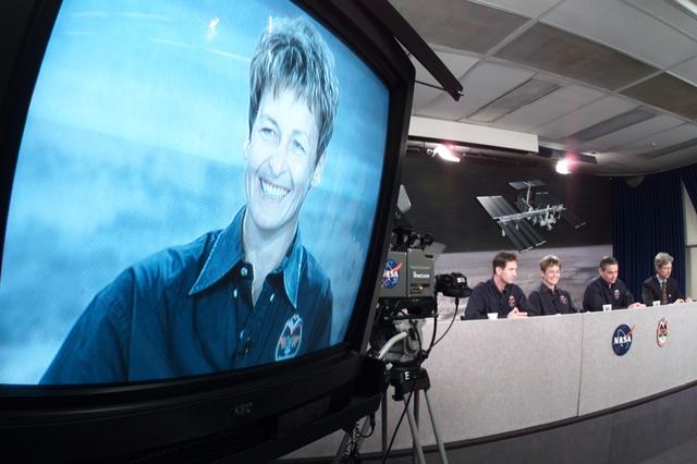 JSC2002-E-21247 (20 May 2002) --- A close-up image of astronaut Peggy A. Whitson, Expedition Five flight engineer, shows on a nearby television monitor during a pre-flight press conference at Johnson Space Center (JSC). The entire crew can be seen in the background.
