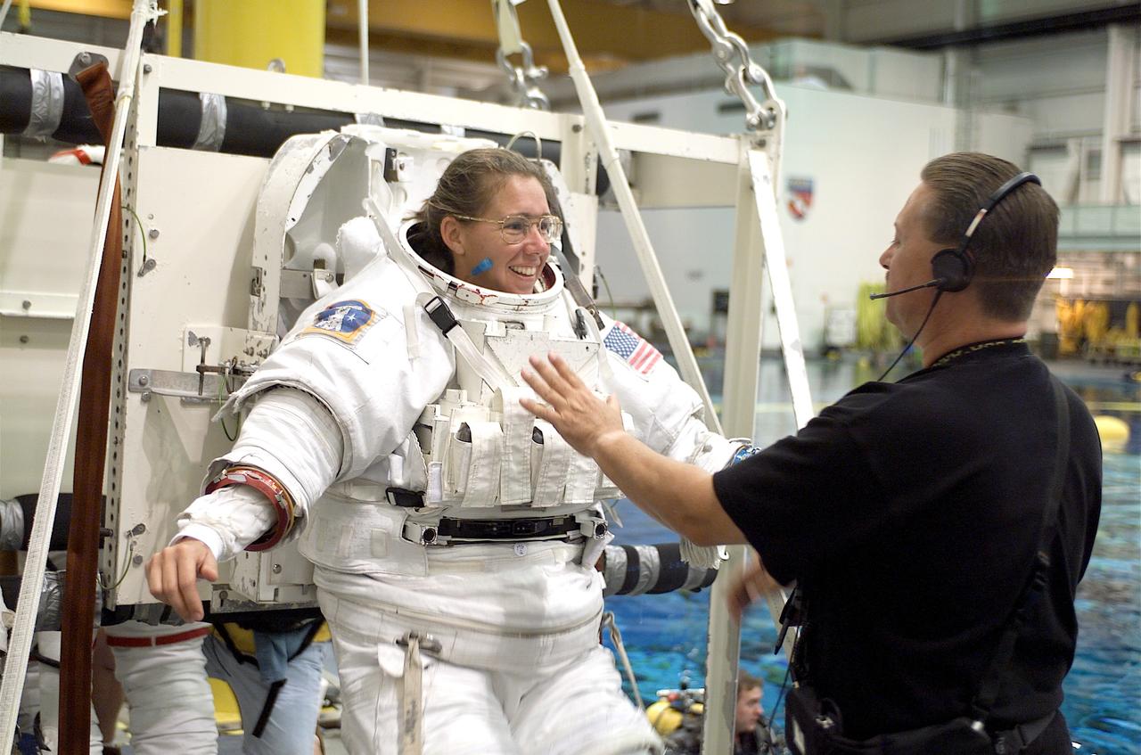 JSC2002-E-22539 (28 May 2002) --- Astronaut Sandra H. Magnus, STS-112 mission specialist, is photographed as the final touches are made on the training version of the Extravehicular Mobility Unit (EMU) space suit prior to being submerged in the waters of the Neutral Buoyancy Laboratory (NBL) near the Johnson Space Center (JSC). United Space Alliance (USA) crew trainer Don Kestler assisted Magnus.