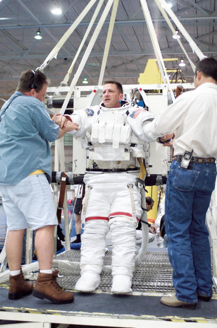 JSC2002-E-23077 (28 May 2002) --- Astronaut Christopher J. (Gus) Loria, STS-113 pilot, is photographed as the final touches are made on the training version of the Extravehicular Mobility Unit (EMU) space suit prior to being submerged in the waters of the Neutral Buoyancy Laboratory (NBL) near the Johnson Space Center (JSC). Fellow crewmember John B. Herrington (right), mission specialist, and United Space Alliance (USA) crew trainer Brian Rhodes assisted Loria.