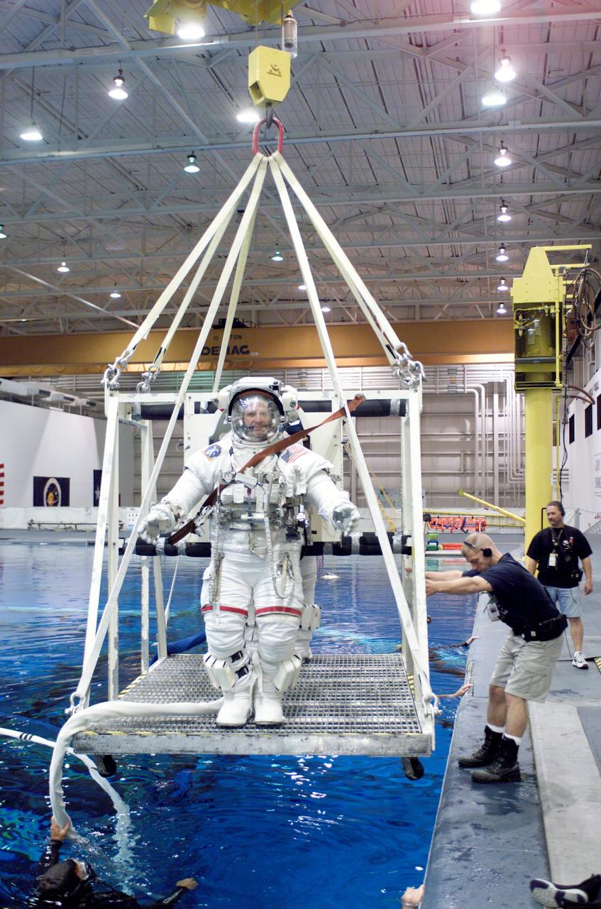 JSC2002-E-23081 (28 May 2002) --- Astronaut Christopher J. (Gus) Loria, STS-113 pilot, and another crewmember (obscured) are about to be submerged in the waters of the Neutral Buoyancy Laboratory (NBL) near the Johnson Space Center (JSC). Loria and his crewmate are wearing the training version of the Extravehicular Mobility Unit (EMU) space suit. Scuba divers are in the water to assist the astronauts in their rehearsal, intended to help prepare them for work on the exterior of the International Space Station (ISS).