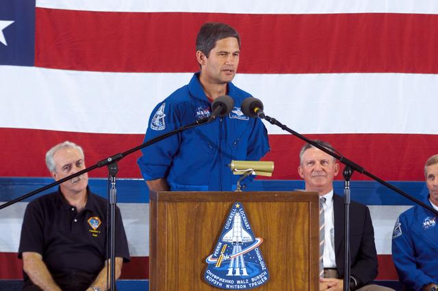 JSC2002-E-25979 (21 June 2002) --- Astronaut Paul S. Lockhart, STS-111 pilot, speaks to a large crowd who showed up at Ellington Field's Hangar 990 to welcome home the STS-111 and Expedition Four crew members. At left background is NASA Administrator Sean O'Keefe. JSC Director Jefferson D. Howell, Jr., is seated immediately to the right of the lectern. The four shuttle prime crew members returned to Earth earlier in the week after two weeks in space, but for the three station crew members, this was their first time in Houston since December of 2001, having spent well over six months in Earth orbit on board the International Space Station (ISS).