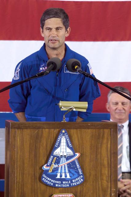 JSC2002-E-25980 (21 June 2002) --- Astronaut Paul S. Lockhart, STS-111 pilot, speaks to a large crowd who showed up at Ellington Field's Hangar 990 to welcome home the STS-111 and Expedition Four crew members. In background is JSC Director Jefferson D. Howell, Jr., seated immediately to the right of the lectern. The four shuttle prime crew members returned to Earth earlier in the week after two weeks in space, but for the three station crew members, this was their first time in Houston since December of 2001, having spent well over six months in Earth orbit on board the International Space Station (ISS).