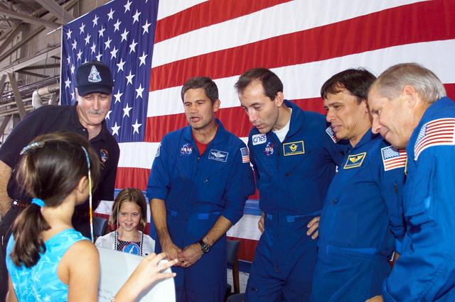 JSC2002-E-25983 (21 June 2002) ---   NASA Administrator Sean O'Keefe (from left), astronauts Paul S. Lockhart, Philippe Perrin, Franklin R. Chang-Diaz and Kenneth D. Cockrell check out the welcome home sign of a young greeter during crew return ceremonies in Hangar 990 at Elligngton Field.