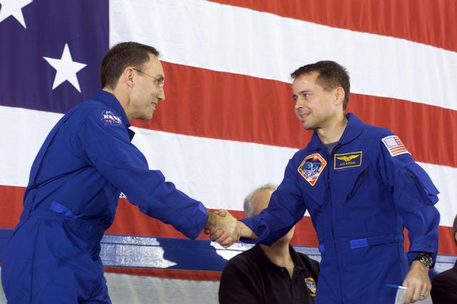 JSC2002-E-26037 (21 June 2002) --- Astronauts Carl E. Walz (left) and Daniel W. Bursch, both Expedition Four flight engineers, shake hands in Hangar 990 at Ellington Field during the STS-111 and Expedition Four crew return ceremonies.