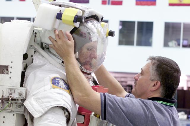 JSC2002-E-27062 (1 July 2002) --- Astronaut Piers J. Sellers, STS-112 mission specialist, dons a training version of the Extravehicular Mobility Unit (EMU) space suit prior to being submerged in the waters of the Neutral Buoyancy Laboratory (NBL) near the Johnson Space Center (JSC). Cosmonaut Fyodor N. Yurchikhin, mission specialist representing Rosaviakosmos, assisted Sellers.
