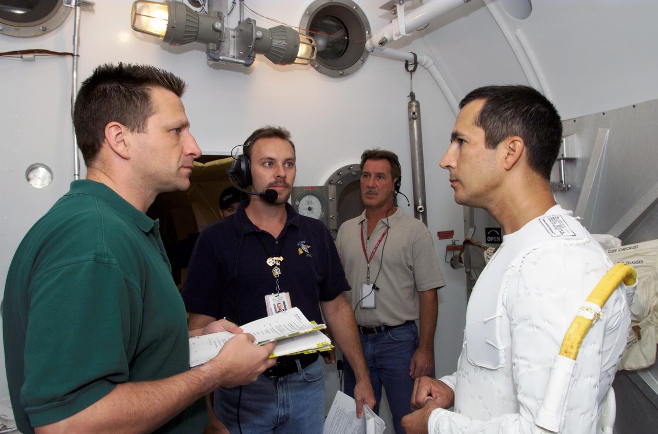JSC2002-E-28168 (16 July 2002) --- Astronaut John B. Herrington (right), STS-113 mission specialist, prepares for an Extravehicular Mobility Unit (EMU) fit check in a Space Station Airlock Test Article (SSATA) in the Crew Systems Laboratory at the Johnson Space Center (JSC). Herrington is wearing the liquid cooling and ventilation garment that complements the EMU space suit. Astronaut Christopher J. (Gus) Loria (left), pilot, and technicians assisted Herrington.