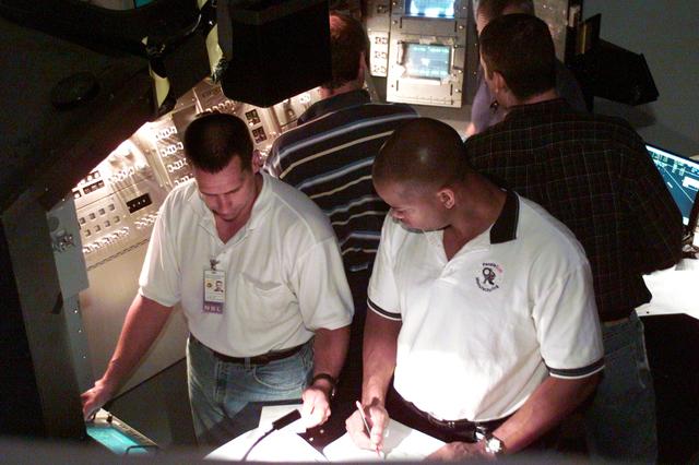 JSC2002-E-28564 (19 July 2002) --- Astronauts William A. Oefelein (left) and Robert L. Curbeam, Jr., STS-116 pilot and mission specialist, respectively, participate in a simulation exercise in the system engineering simulator in the Avionics Systems Laboratory at the Johnson Space Center (JSC). The facility includes moving scenes of full-sized International Space Station (ISS) components over a simulated Earth.