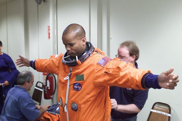 JSC2002-E-33368 (29 July 2002) --- Astronaut Robert L. Curbeam, Jr., STS-116 mission specialist, dons his training version of the shuttle launch and entry suit prior to the start of a mission training session in the Jake Garn Simulation and Training Facility at the Johnson Space Center (JSC). United Space Alliance (USA) suit technician Daniel Palmer assisted Curbeam.