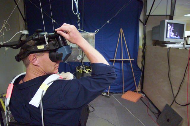 JSC2002-E-34618 (21 August 2002) --- Astronaut Piers J. Sellers, STS-112 mission specialist, uses virtual reality hardware in the Space Vehicle Mockup Facility at the Johnson Space Center (JSC) to rehearse some of his duties on the upcoming mission to the International Space Station (ISS). This type of virtual reality training allows the astronauts to wear a helmet and special gloves while looking at computer displays simulating actual movements around the various locations on the International Space Station (ISS) hardware with which they will be working.