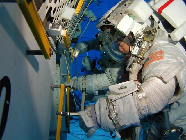 JSC2002-E-40332 (20 September 2002) --- Astronaut Soichi Noguchi, STS-114 mission specialist, wears a training version of the Extravehicular Mobility Unit (EMU) spacesuit during an underwater simulation of extravehicular activity (EVA) scheduled for the 17th shuttle mission to the International Space Station (ISS). Astronaut Stephen K. Robinson (partially obscured), mission specialist, joined Noguchi for the simulation, conducted in the Neutral Buoyancy Laboratory (NBL) near the Johnson Space Center (JSC). Noguchi represents Japan’s National Space Development Agency (NASDA).