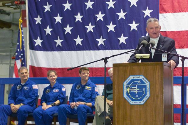 JSC2002-E-42177 (19 October 2002) --- Lt. General Jefferson D. Howell, Jr., JSC Director, addresses a crowd on hand at Ellington Field's Hangar 990 during crew return ceremonies for the STS-112  crewmembers.  Pictured in the background, from the left, are astronauts David A. Wolf, mission specialist; Pamela A. Melroy, pilot; and Jeffrey S. Ashby, mission commander.  NASA Administrator Sean O'Keefe is partially obscured by the lectern.