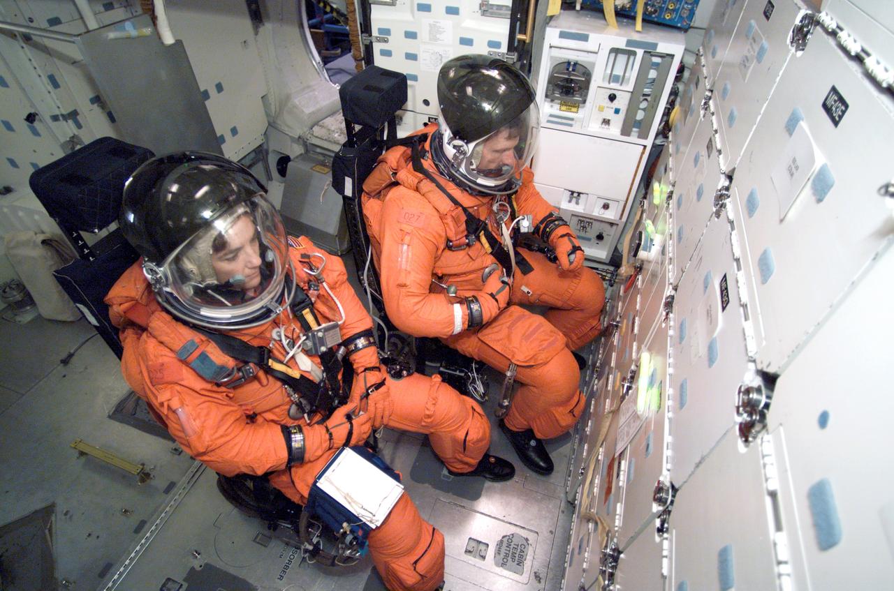 JSC2002-E-44123 (31 October 2002) --- Astronauts Heidemarie M. Stefanyshyn-Piper (left) and Joseph R. (Joe) Tanner, both STS-115 mission specialists, participate in mission training in one of the high fidelity trainers/mockups in the Space Vehicle Mockup Facility at the Johnson Space Center (JSC). The two, attired in training versions of the full-pressure launch and entry suit, are seated on the middeck for an emergency egress training session.