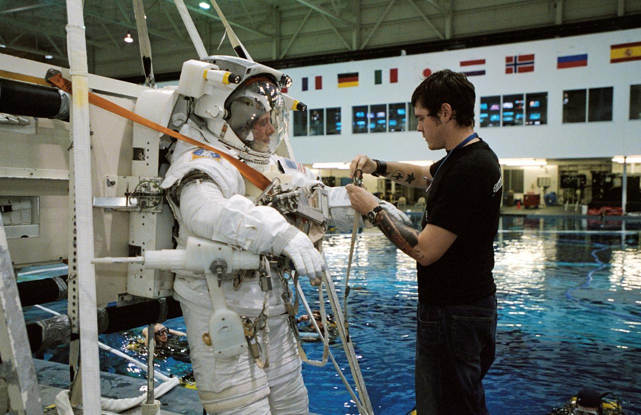 JSC2003-00004 (7 January 2003) --- Astronaut Christer Fuglesang, STS-116 mission specialist, gets help with final touches on the training version of his Extravehicular Mobility Unit (EMU) spacesuit prior to being submerged in the waters of the Neutral Buoyancy laboratory (NBL) at the Johnson Space Center (JSC). Fuglesang represents the European Space Agency (ESA).