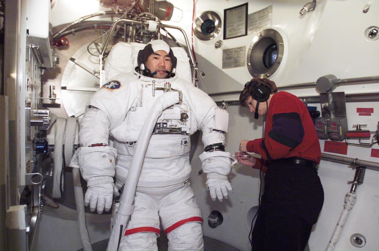 JSC2003-E-01128 (10 January 2003) --- Astronaut Soichi Noguchi, STS-114 mission specialist, participates in an Extravehicular Mobility Unit (EMU) spacesuit fit check in the Space Station Airlock Test Article (SSATA) in the Crew Systems Laboratory at the Johnson Space Center (JSC). Astronaut Eileen M. Collins, mission commander, assisted Noguchi, who represents the Japanese Space Agency.