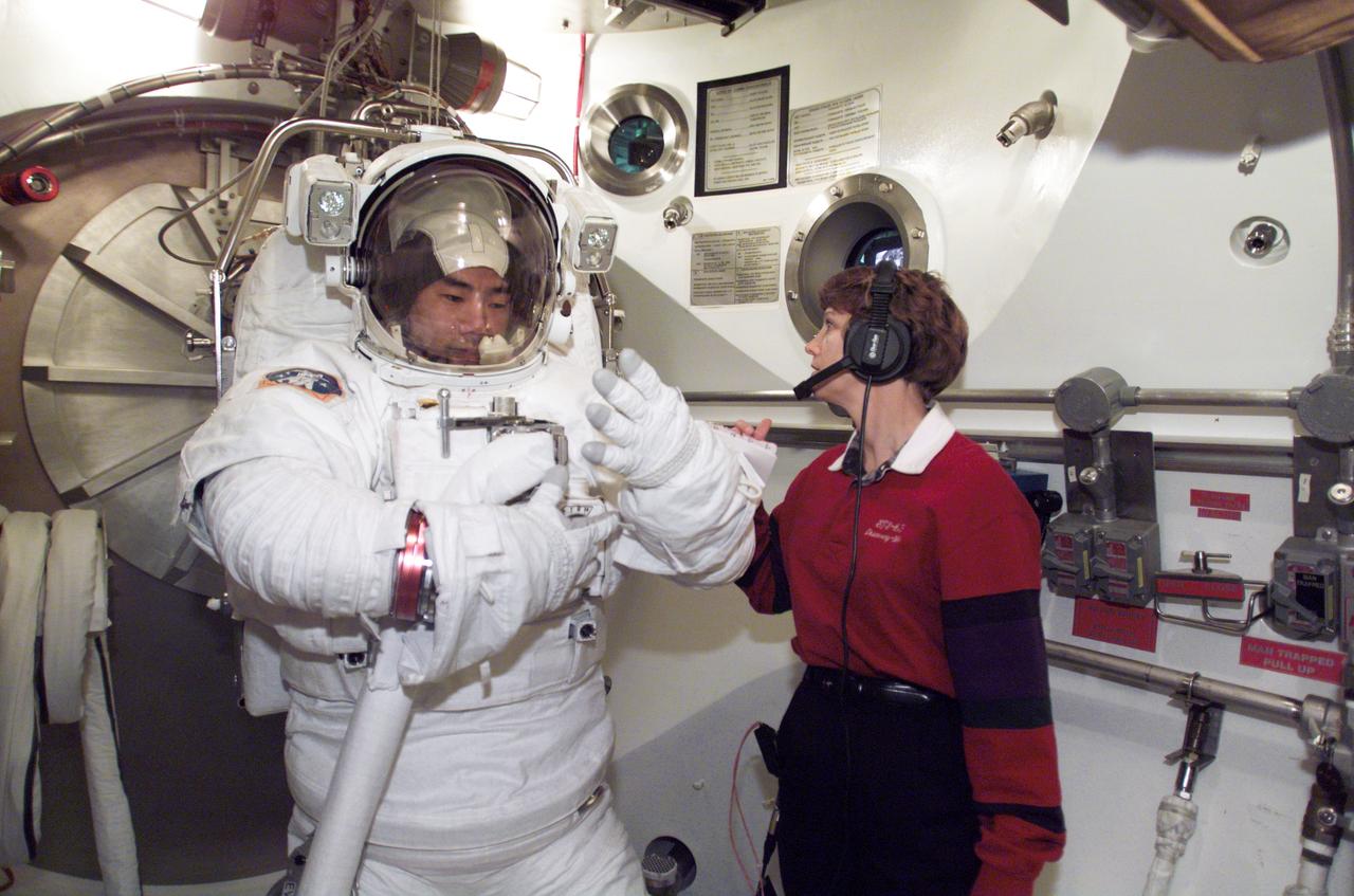 JSC2003-E-01130 (10 January 2003) --- Astronaut Soichi Noguchi, STS-114 mission specialist, participates in an Extravehicular Mobility Unit (EMU) spacesuit fit check in the Space Station Airlock Test Article (SSATA) in the Crew Systems Laboratory at the Johnson Space Center (JSC). Astronaut Eileen M. Collins, mission commander, assisted Noguchi, who represents the Japanese Space Agency.