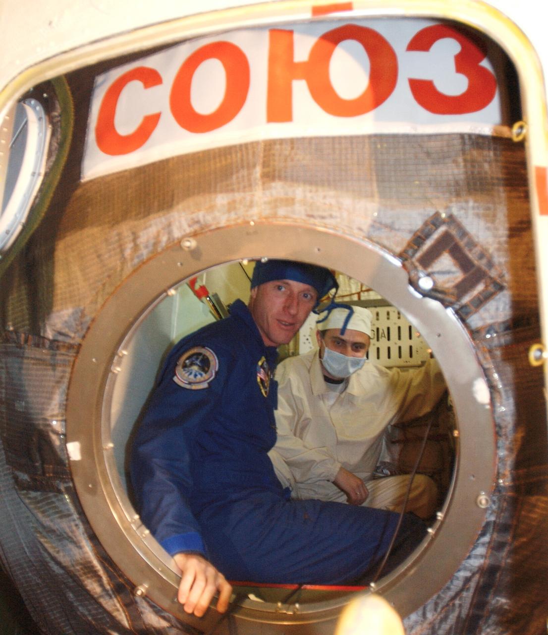 JSC2003-E-59057 (13 October 2003) --- Astronaut C. Michael Foale (left), Expedition 8 mission commander and NASA ISS science officer, is briefed by a technician inside the Soyuz TMA-3 vehicle in a processing facility at the Baikonur Cosmodrome in Kazakhstan during a pre-launch inspection of the spacecraft. Expedition 8 is scheduled to launch from the Baikonur Cosmodrome on October 18 onboard a Soyuz rocket to the International Space Station (ISS). Photo Credit: NASA/Bill Ingalls
