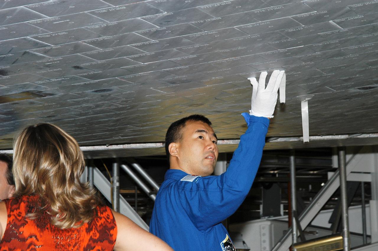 JSC2003-E-61577 (30 October 2003) --- Astronaut Soichi Noguchi, STS-114 mission specialist representing Japan Aerospace Exploration Agency (JAXA), takes a close look at tiles underneath the Space Shuttle Atlantis in the Orbiter Processing Facility at Kennedy Space Center (KSC). The crew is at KSC to take part in hands-on equipment and orbiter familiarization.