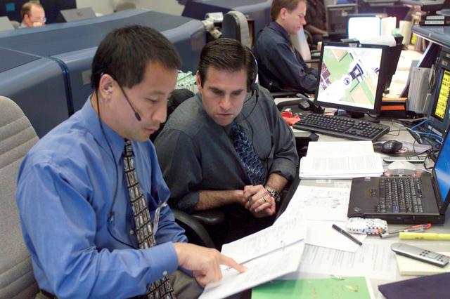 JSC2004-E-19651 (20 April 2004) --- Astronauts Edward T. Lu (left) and Gregory E. Chamitoff, discuss data at the spacecraft communicator (CAPCOM) console in the shuttle flight control room (WFCR) in Houston?s Mission Control Center (MCC) during rendezvous and docking operations between the Soyuz TMA-4 spacecraft and the International Space Station (ISS). The Soyuz, which carried cosmonaut Gennady I. Padalka, Russia?s Federal Space Agency Expedition 9 commander; astronaut Edward M. (Mike) Fincke, NASA ISS science officer and flight engineer; and European Space Agency (ESA) astronaut Andre Kuipers of the Netherlands, docked with the Station at 12:01 a.m. (CDT) on April 21, 2004.