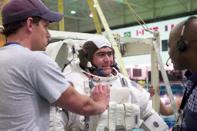 JSC2004-E-34992 (9 August 2004) --- Cosmonaut Salizhan S. Sharipov, Expedition 10 flight engineer representing Russia;s Federal Space Agency, gets help with final touches on a training version of the Extravehicular Mobility Unit (EMU) spacesuit prior to being submerged in the waters of the Neutral Buoyancy laboratory (NBL) at the Johnson Space Center (JSC). Kevin Moore (left) and Carl Wright, both with United Space Alliance (USA), assisted Sharipov.